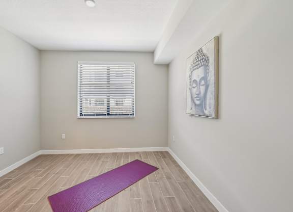 A yoga mat is on the floor of a room with a picture of Buddha on the wall.