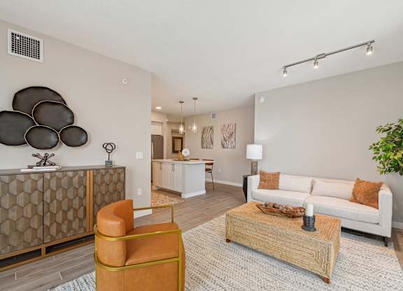 A living room with a white couch, a wooden coffee table, and a large abstract sculpture on the wall.