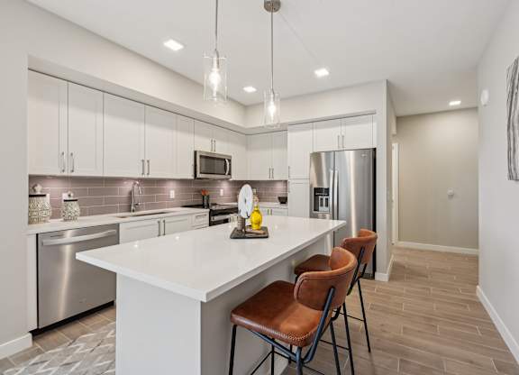 A modern kitchen with a white island and stainless steel appliances.