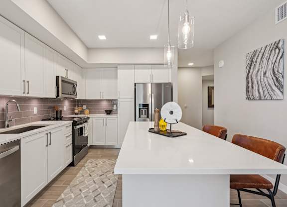 A modern kitchen with a white island and stainless steel appliances.