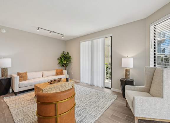 A living room with a white couch, a brown ottoman, and a grey rug.