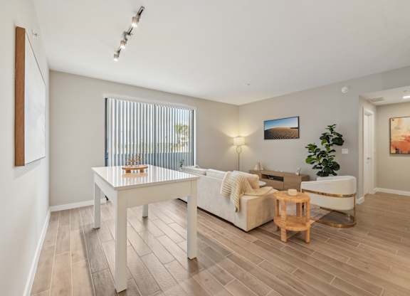 A living room with a white couch, a wooden coffee table, and a plant.