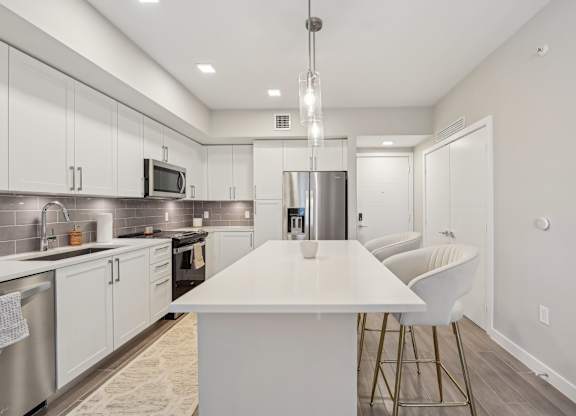 A modern kitchen with a white island and stainless steel appliances.