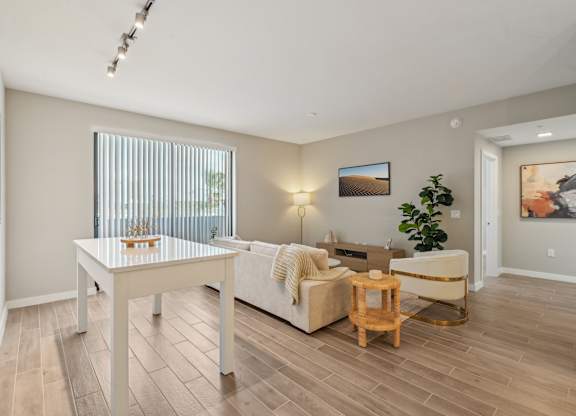 A living room with a white couch, a wooden coffee table, and a painting on the wall.