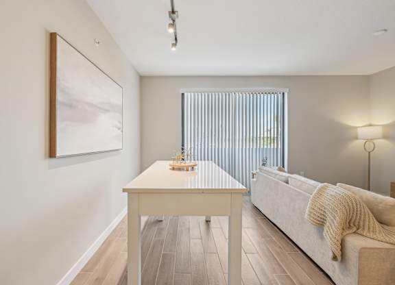 A modern living room with a white couch and a painting on the wall.