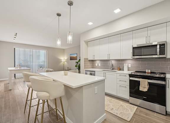 A modern kitchen with a white island and bar stools.