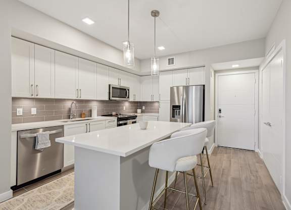 A modern kitchen with a white island and stainless steel appliances.