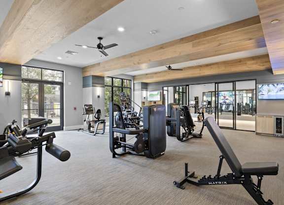 a gym with weights and cardio machines and glass doors at Mayla Pompano, Pompano Beach