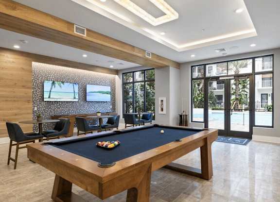 a pool table in a room with a tv and chairs at Mayla Pompano, Pompano Beach, FL