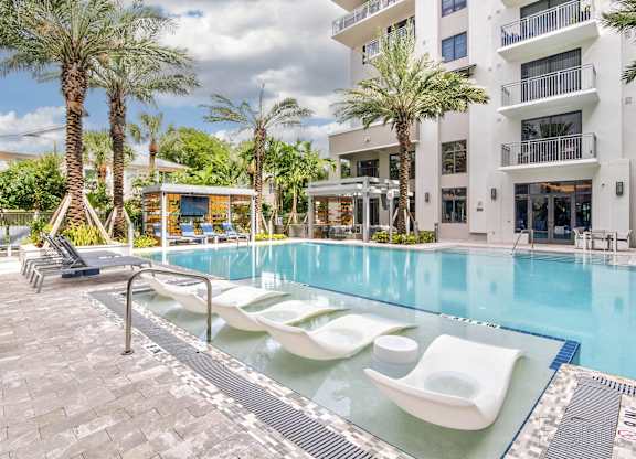 A pool with sun loungers and a building at Mayla Pompano, Pompano Beach