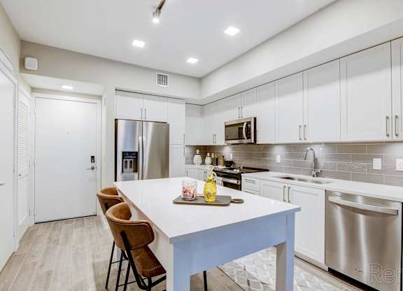 A kitchen with a white table and stainless steel appliances at Mayla Pompano, Pompano Beach, FL