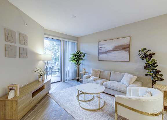 A living room with a white couch, a coffee table, and a potted plant.
