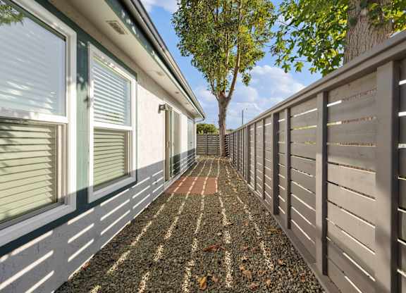 A long, narrow walkway between two walls with a tree in the distance.