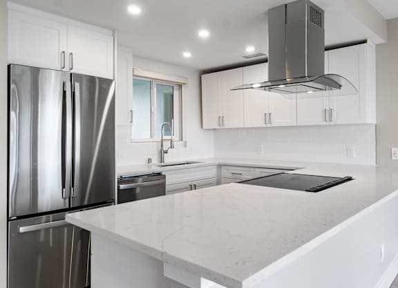A modern kitchen with a marble countertop and stainless steel appliances.