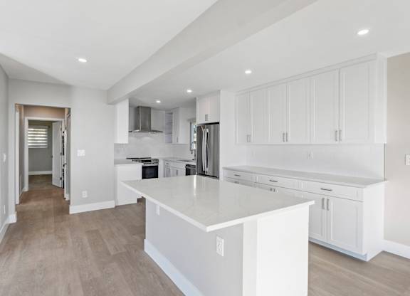 A modern kitchen with white cabinets and a large island.at Ocean Edge @ Laguna Beach, Laguna Beach, CA