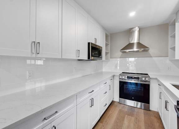 A modern kitchen with white cabinets and a stainless steel oven.
