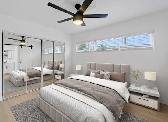 A bedroom with a large bed and a ceiling fan.
