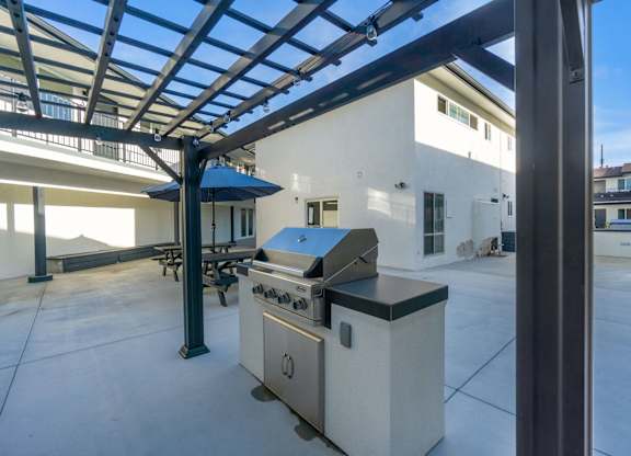 A modern outdoor kitchen area with a grill and a table. at Torrance Gateway Apartments, Torrance, 90501