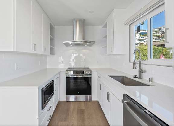 A modern kitchen with white cabinets and stainless steel appliances.at Ocean Edge @ Laguna Beach, California