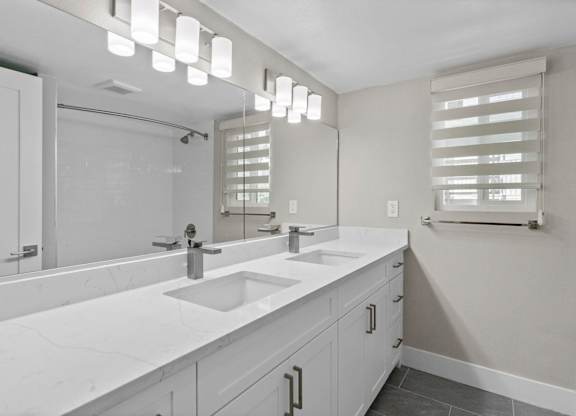 A bathroom with a white countertop and a large mirror.