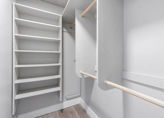 A white shelving unit with a white wall and a white rail.
