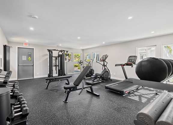 A gym with a variety of equipment including weights, a treadmill, and a stationary bike.