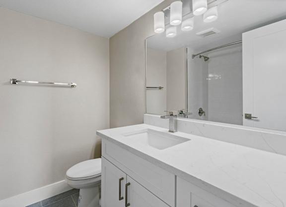 A white bathroom with a toilet, sink, and mirror.