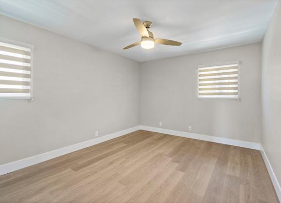 A room with a ceiling fan and wooden flooring.