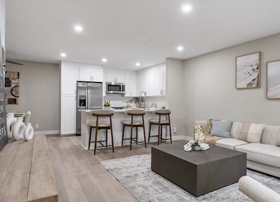 A modern kitchen with a bar area and a living room with a couch at Tamarack Sands Apartment Homes, Carlsbad, California
