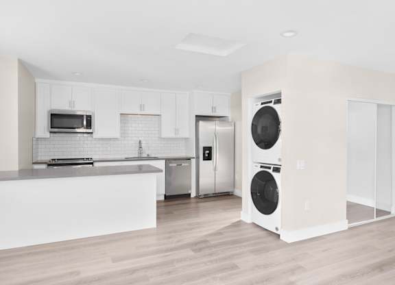 A modern kitchen with a white countertop and stainless steel appliances.