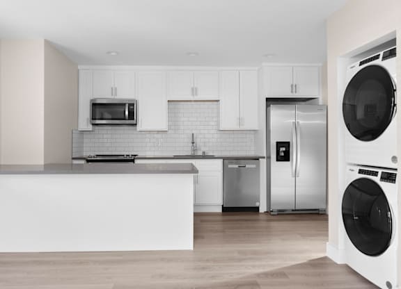 A modern kitchen with a white countertop and stainless steel appliances.