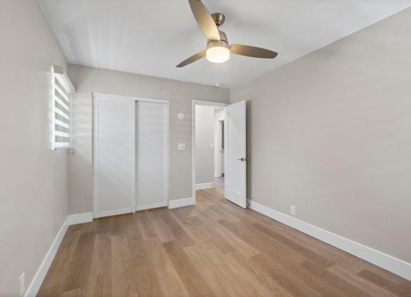 A room with a ceiling fan and wooden flooring.