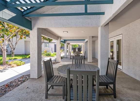 A patio with a table and chairs under a roof.