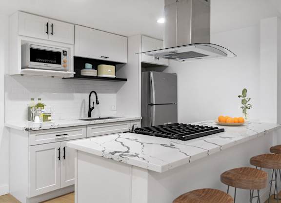 A kitchen with a black and white marble countertop and white cabinets.