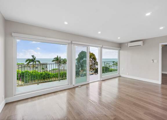 A spacious room with a view of the ocean through large windows.
