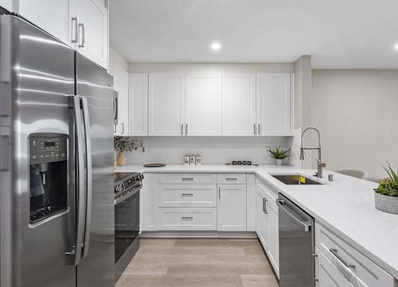 A modern kitchen with a stainless steel refrigerator and white cabinets at Tamarack Sands Apartment Homes, California