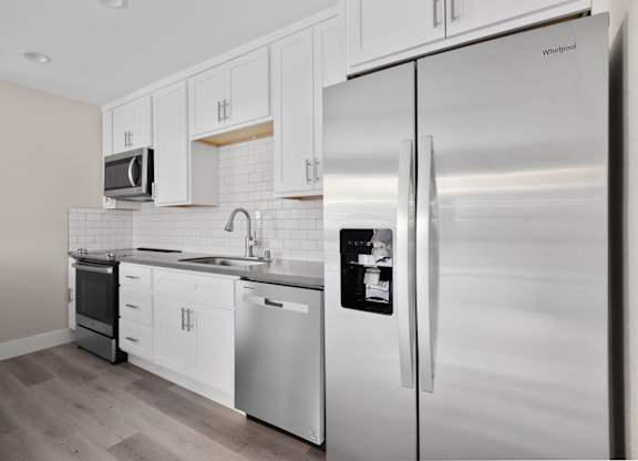 A modern kitchen with a stainless steel refrigerator and white cabinets.