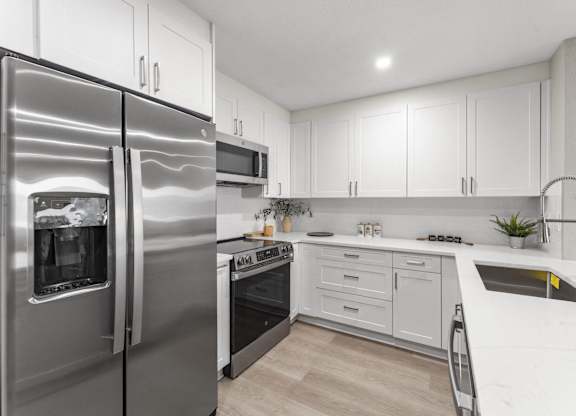 A modern kitchen with a stainless steel refrigerator and white cabinets at Tamarack Sands Apartment Homes, Carlsbad, California