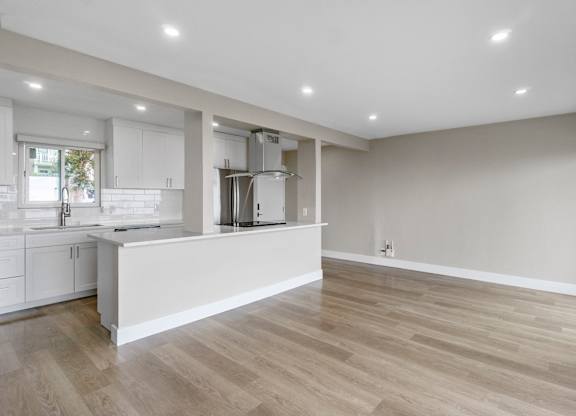 A kitchen with white cabinets and a wooden floor.