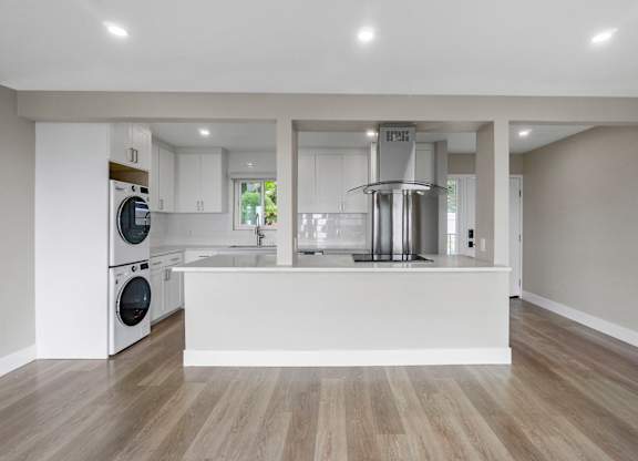 A modern kitchen with a white countertop and wooden flooring.