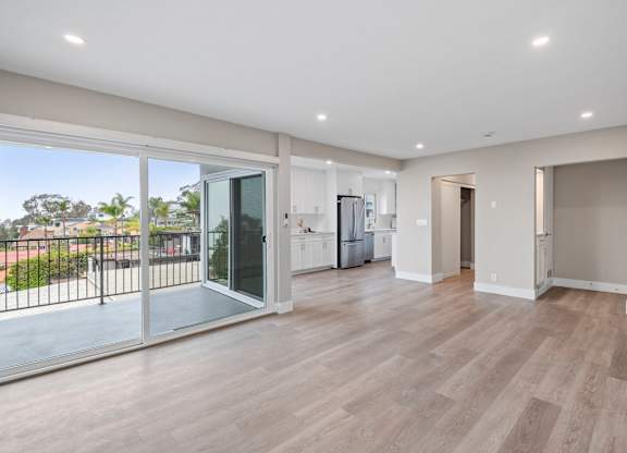 A spacious room with wooden flooring and sliding glass doors.
