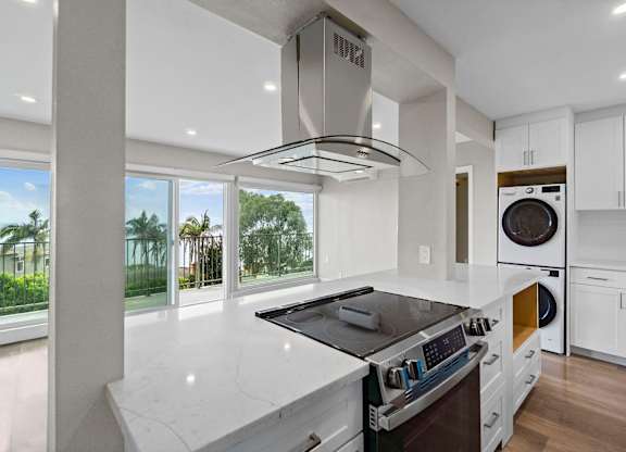 A modern kitchen with a stove top oven and a washing machine built into the cabinetry.