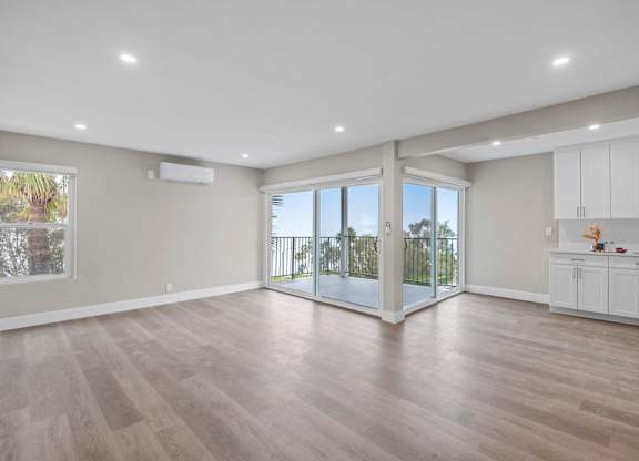 A spacious room with a sliding glass door leading to a balcony.