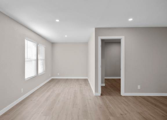 A room with wooden flooring and a doorway leading to another room.