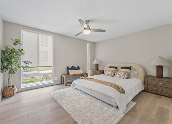 A bedroom with a large bed, a ceiling fan, and a potted plant at Tamarack Sands Apartment Homes, Carlsbad