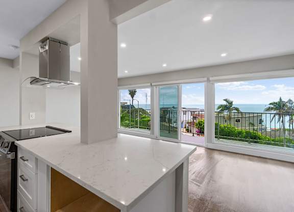 A modern kitchen with a large island and a view of the ocean.