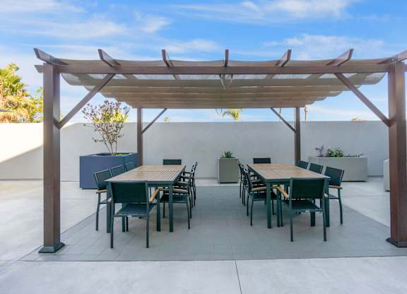 A patio with a table and chairs under a wooden pergola.at The Reserve La Mirada, California, 90638