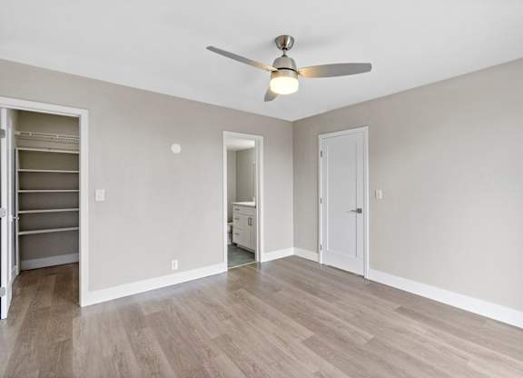 A room with a ceiling fan and light fixture, and a closet with shelves.