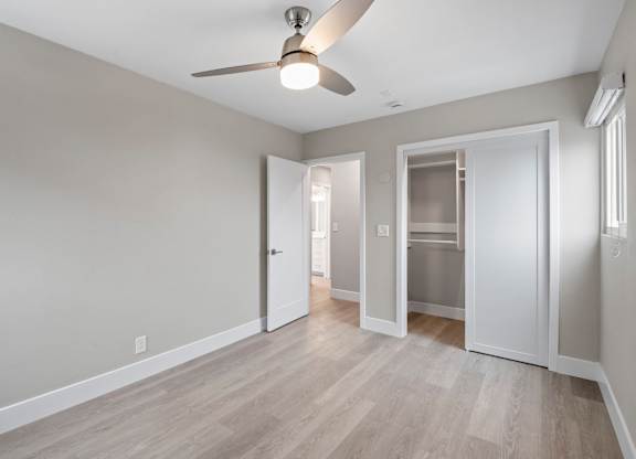A room with a ceiling fan and a door leading to another room.