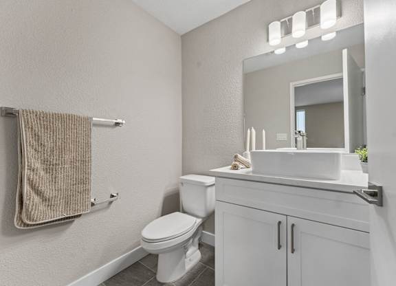 A white bathroom with a toilet, sink, and mirror at Tamarack Sands Apartment Homes, California, 92008